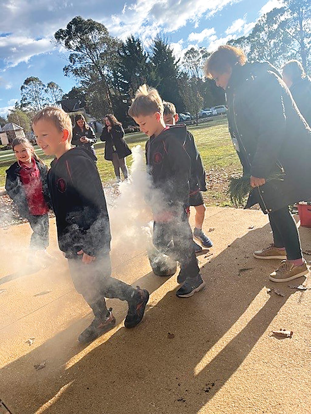 Noah Harrison, Kyle Wilmot and Kurnai elder Linda Mullett participate in the smoking ceremony at Nilma Primary School.