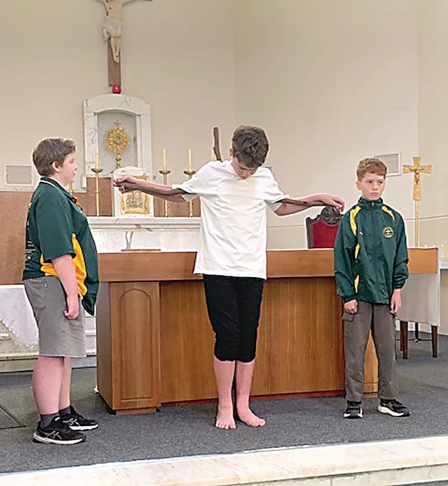 The soldiers played by Owen (left) and Asher (right) put Jesus played by Tom on the cross.