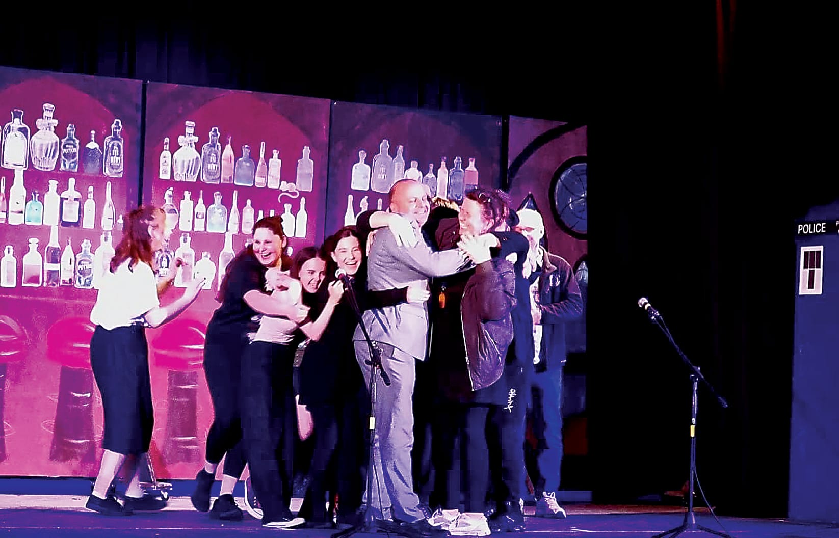 The cast and crew engage in a group hug with their director Yolette Stewart and principal Michael Shone.