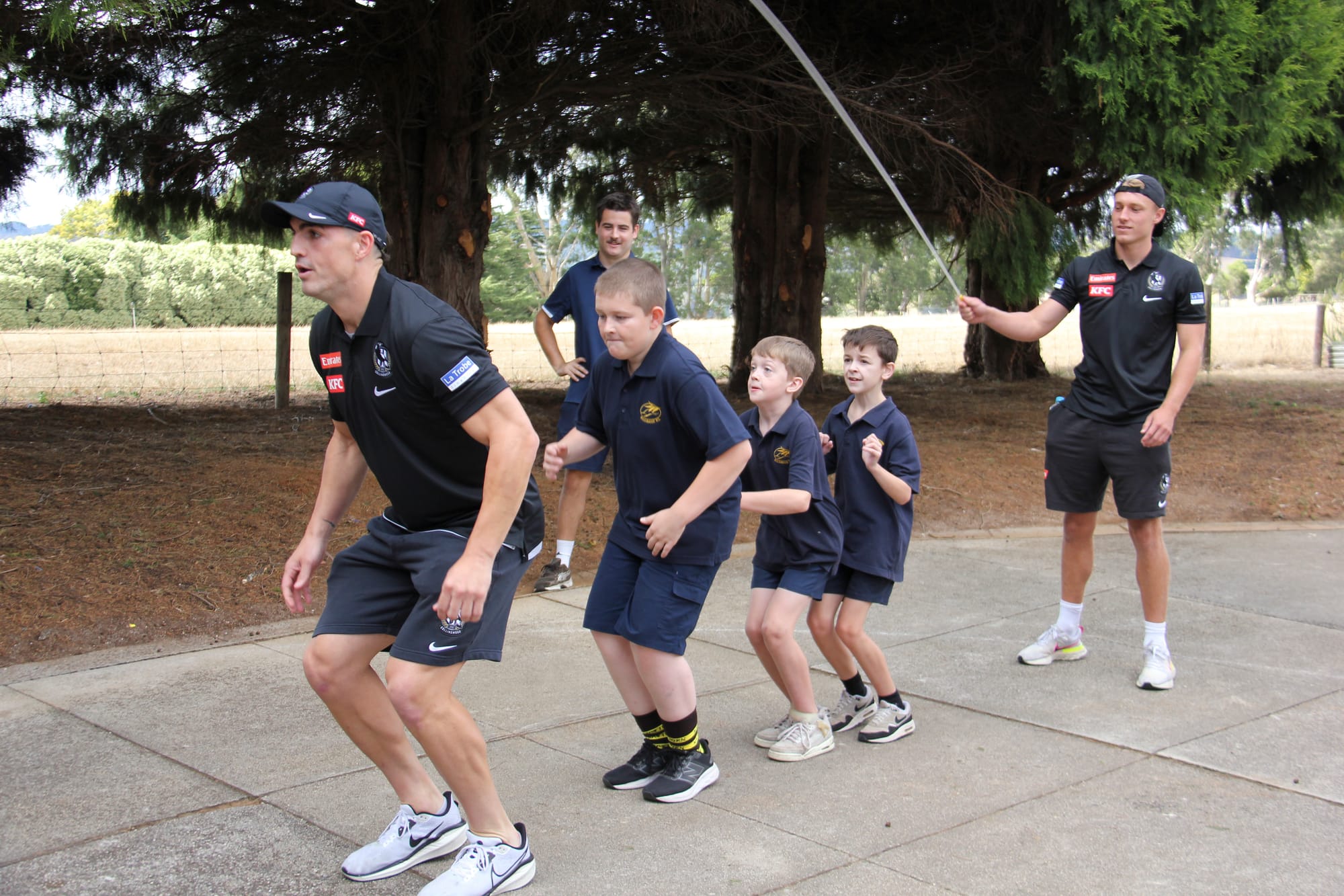 Above: Collingwood defender Brayden Maynard leads Ellinbank Primary School students Samuel Sheil, Ryan Hodgson and Zayne Oldham in a round of jump rope as his teammate Finlay Macrae keeps the tempo.Left: Eden Conroy shows off her jump rope skills to Collingwood's Tew Jiath.