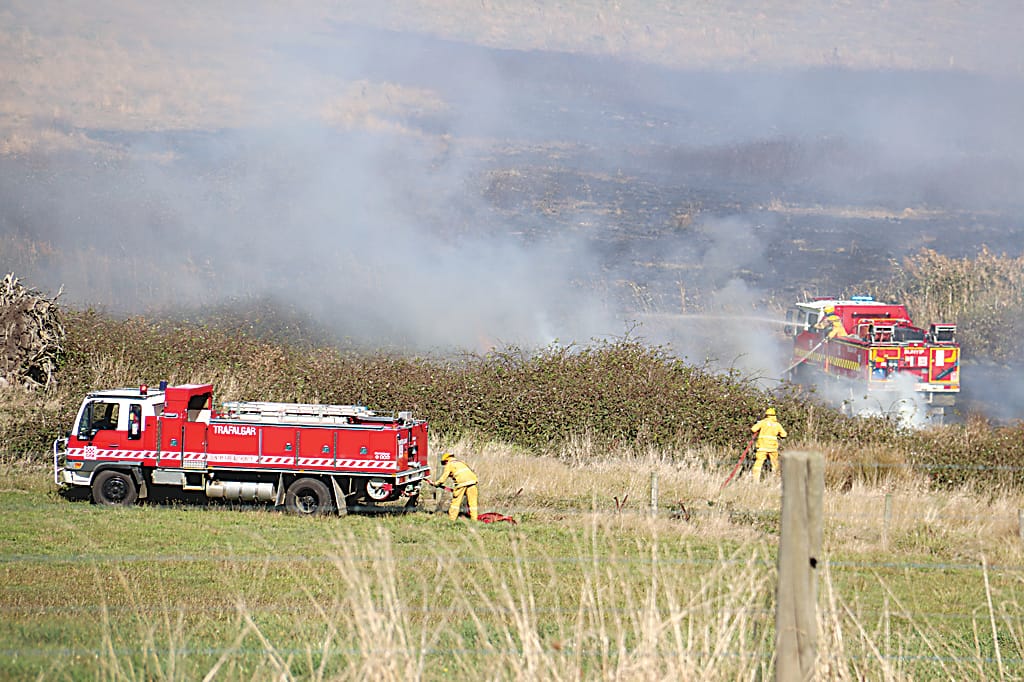 CFA volunteers work to extinguish a 20 acre grassfire in Drouin on Thursday afternoon. The fire was ignited after a suspicious fire at an abandoned farmhouse on Weebar Rd.