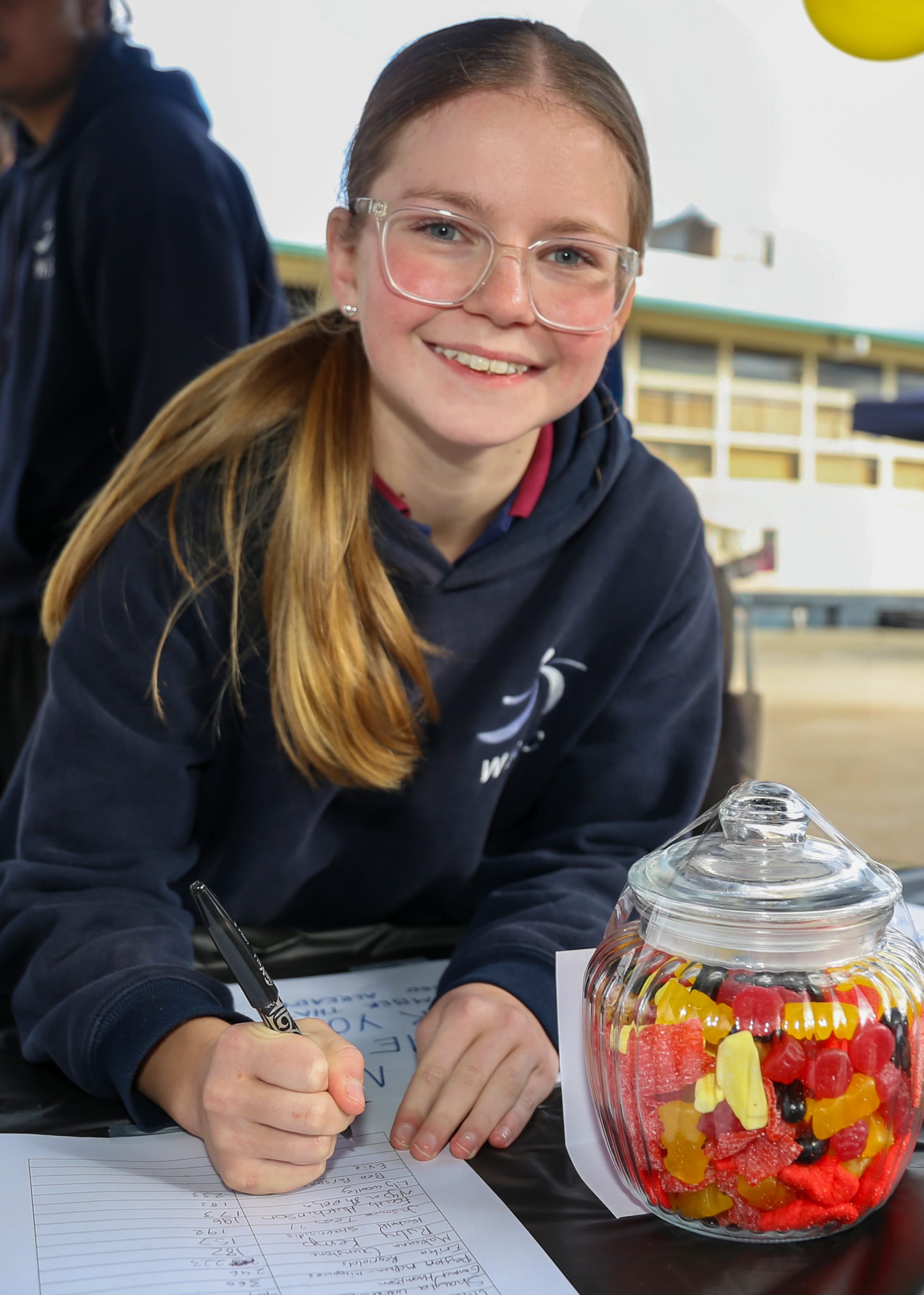 Evie Butler takes a guess of how many lollies are in the jar.