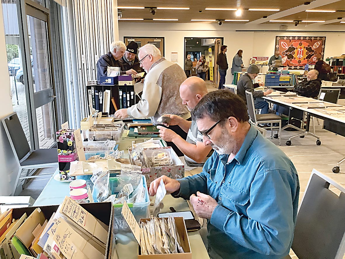 Stamp and coin enthusiasts look through member Stan Rodwell's collection.
