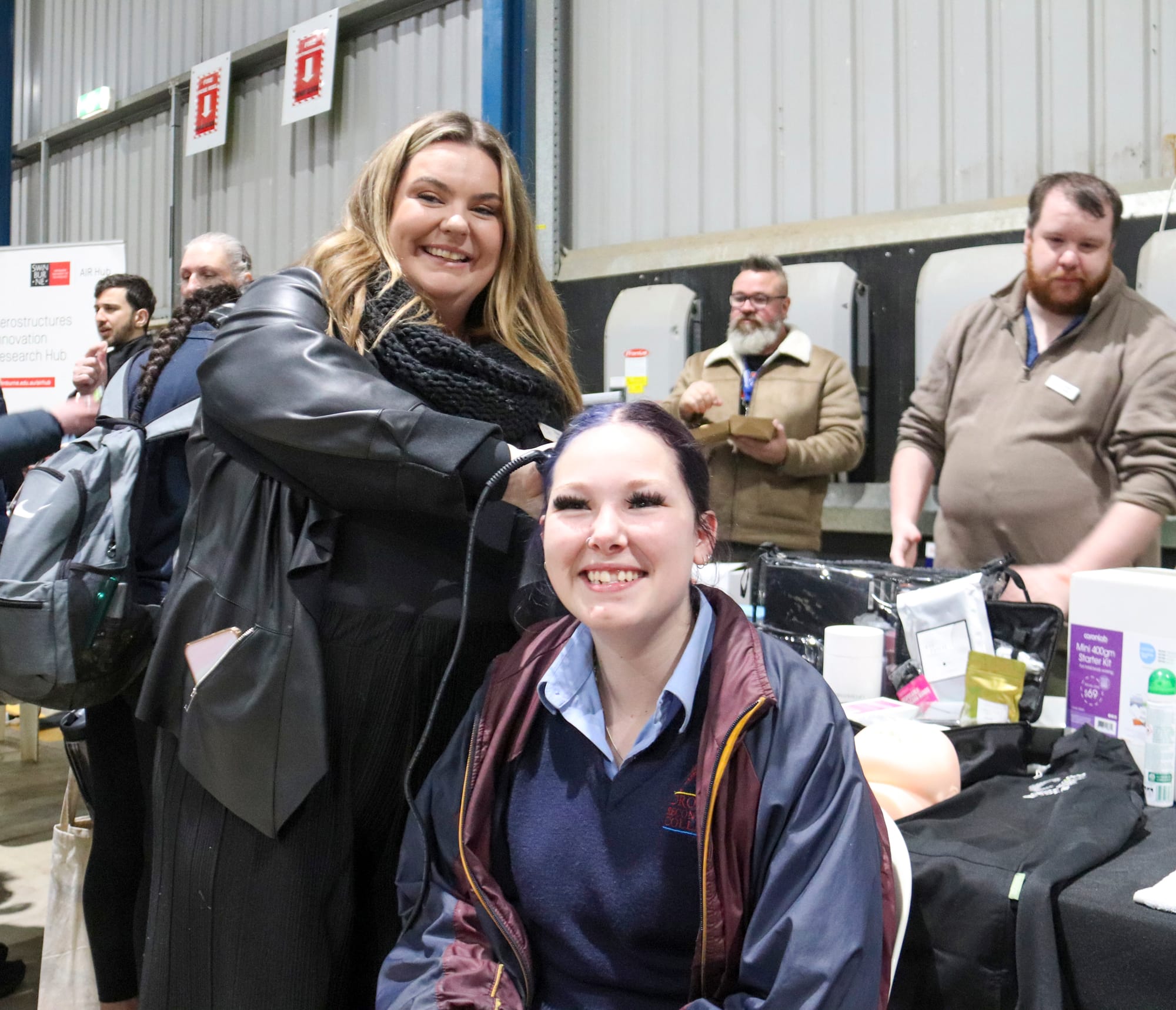 Hayley Naylor curls Sheyane Pratt's hair on the Community College Gippsland stand