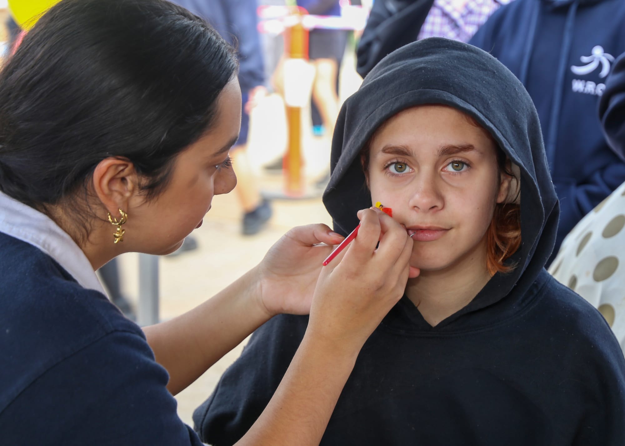 Shalini Verma paints a flag on the face of student Leimaya Cane-Austin.