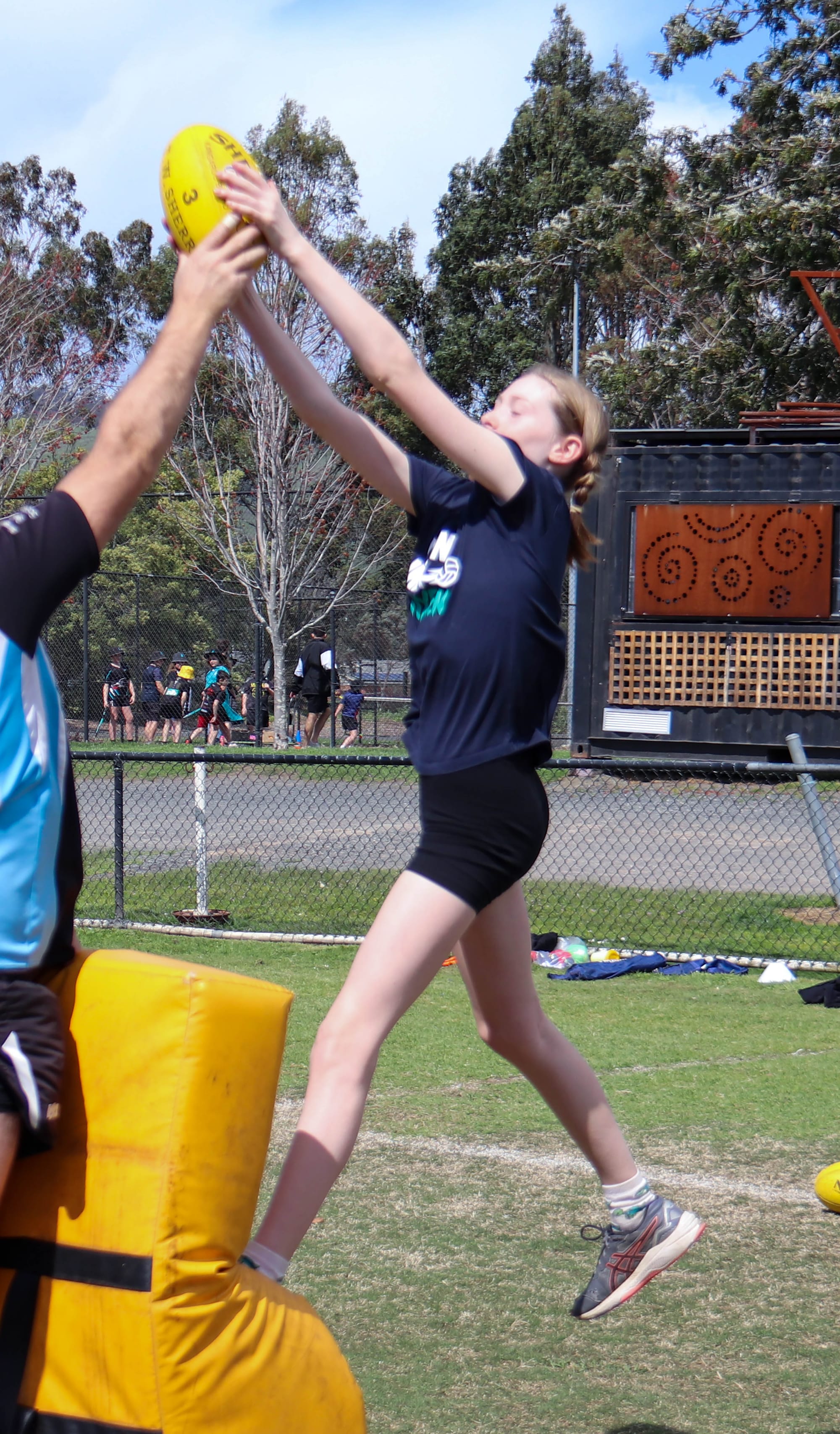 Cora Maye rises high for a mark on the specky bag during the footy.
