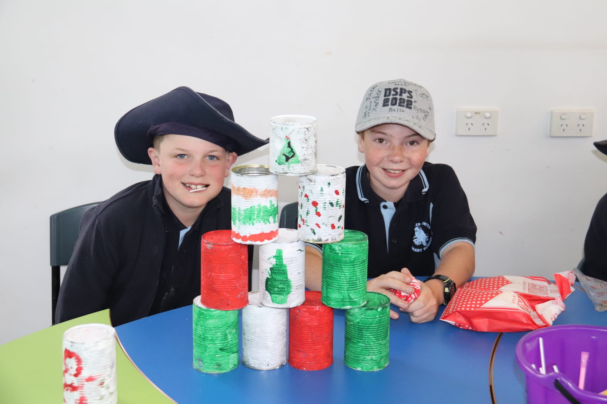 Dylan and Liam show off their stall, where people could throw balls to try and knock over the cans.