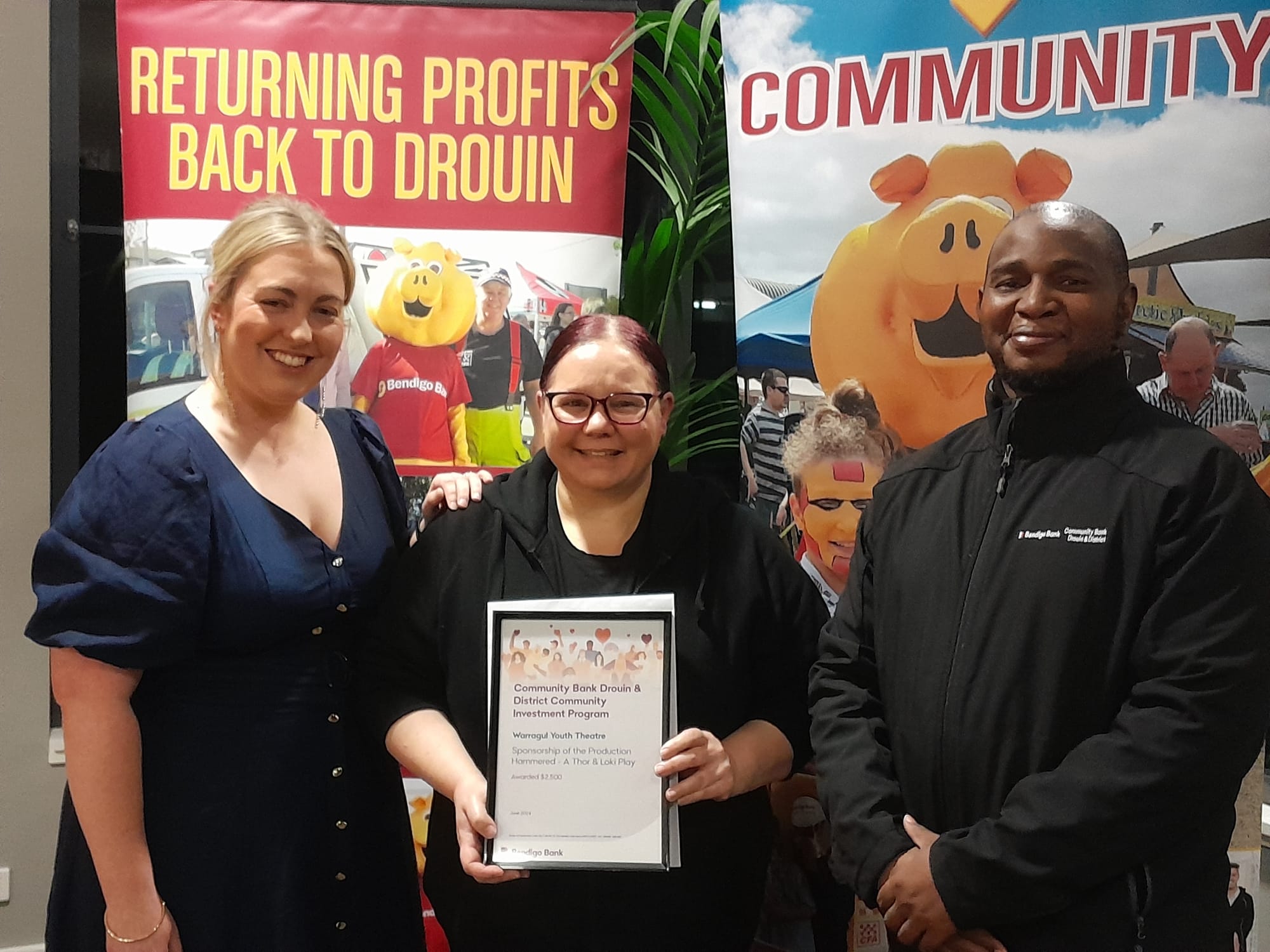 Warragul Youth Theatre's Teigan Bliss and Renee Fallon with bank director Joshua Chikuse.