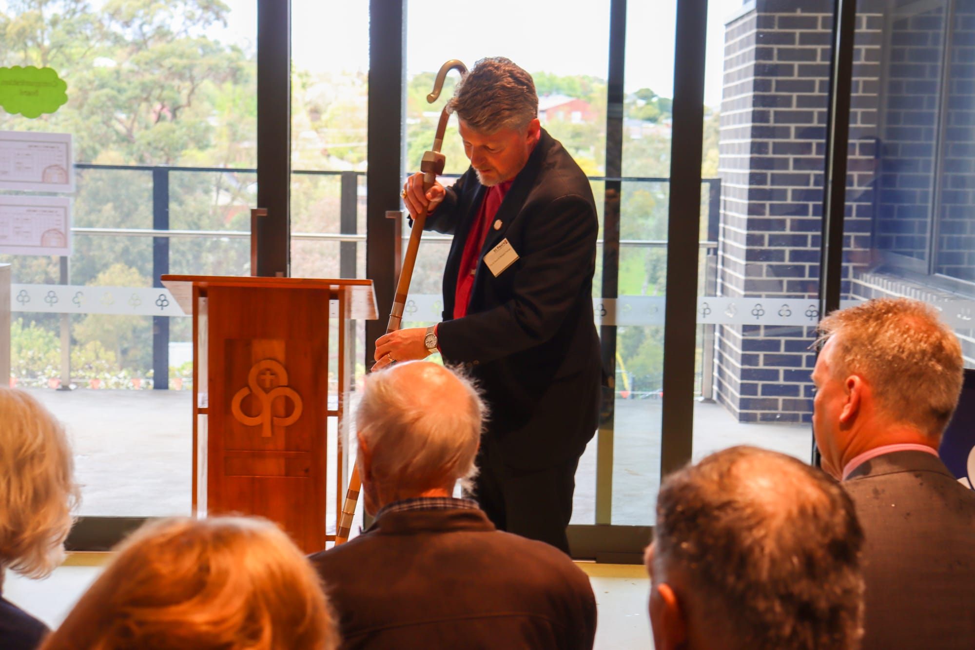 Bishop of Gippsland Richard Treloar makes the sign of the cross on the floor to dedicate the new learning and administration building.