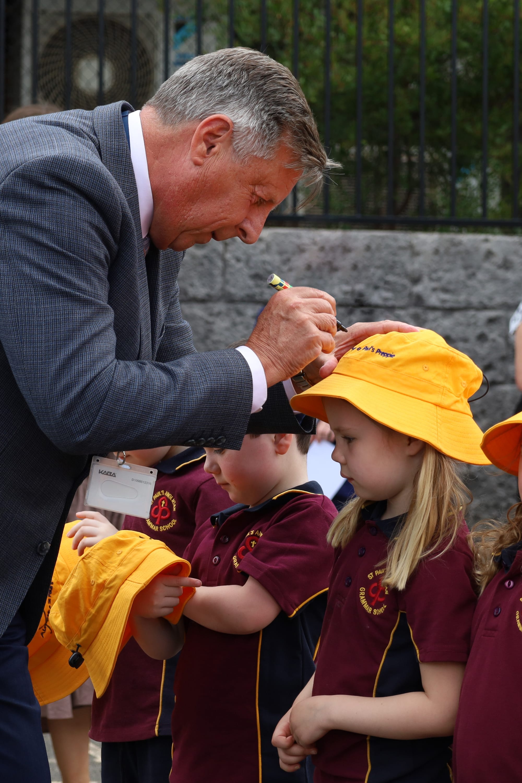Mila Collier has the 'almost' crossed off her yellow prep hat by St Paul's principal Cameron Herbert.