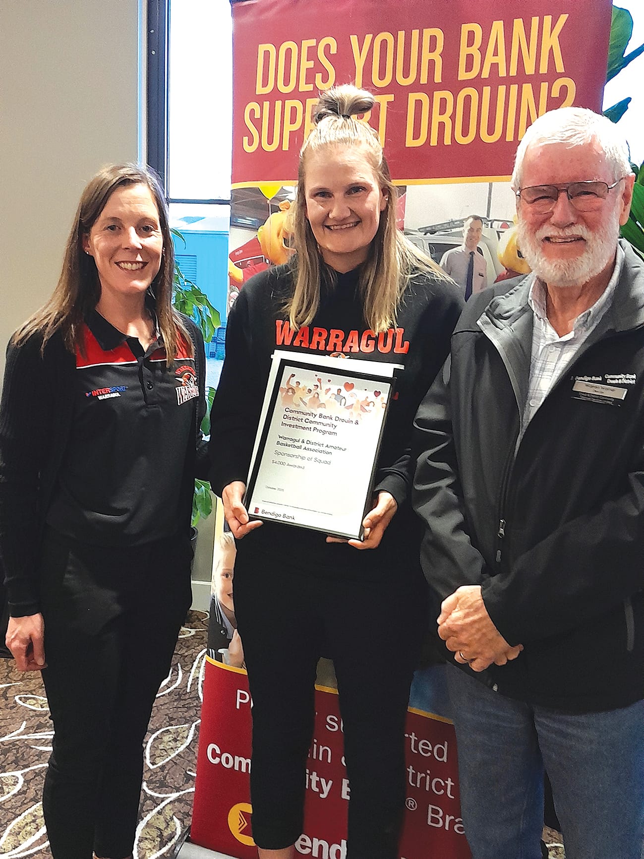 Warragul and District Basketball Association's Janelle Hartmann and Lara Parker with bank director Warren Warner.