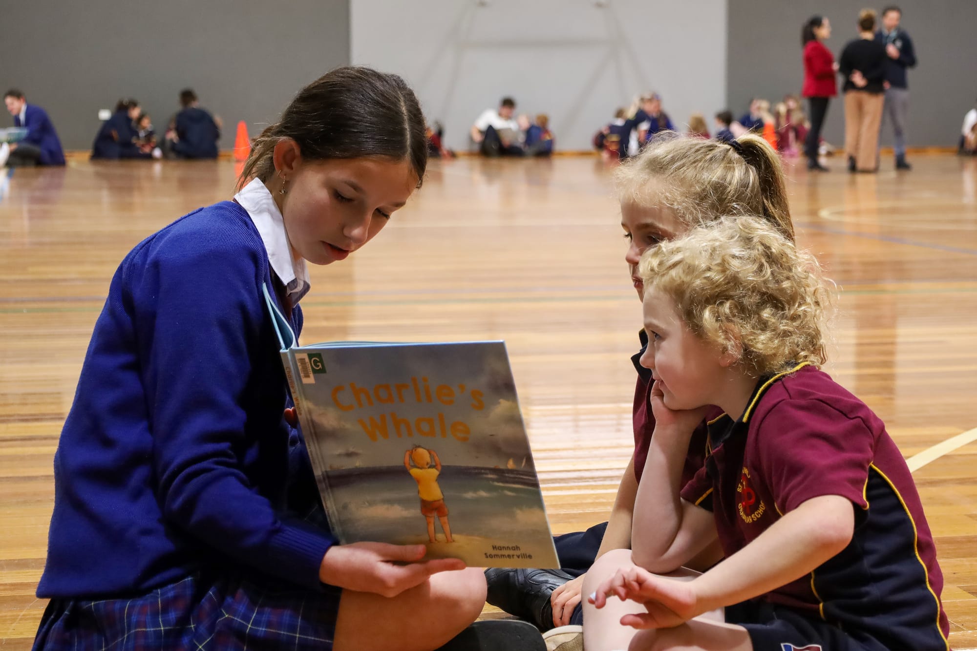 Year 10 student Edie Flanagan reads to Astoria Hornsey and Saskia Shean.