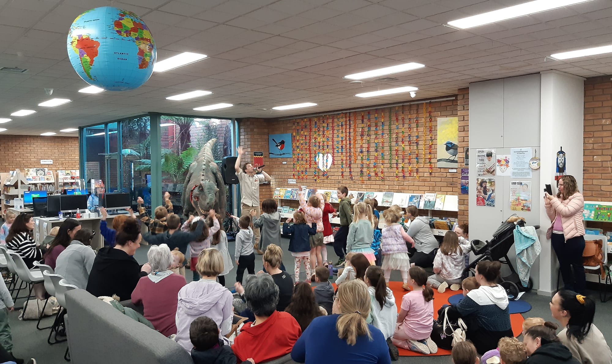 Getting up close to a life-sized dinosaur as part of Myli's school holiday program are Patrick (age two), Tameka Thomson and Bobby McNamara (age five).