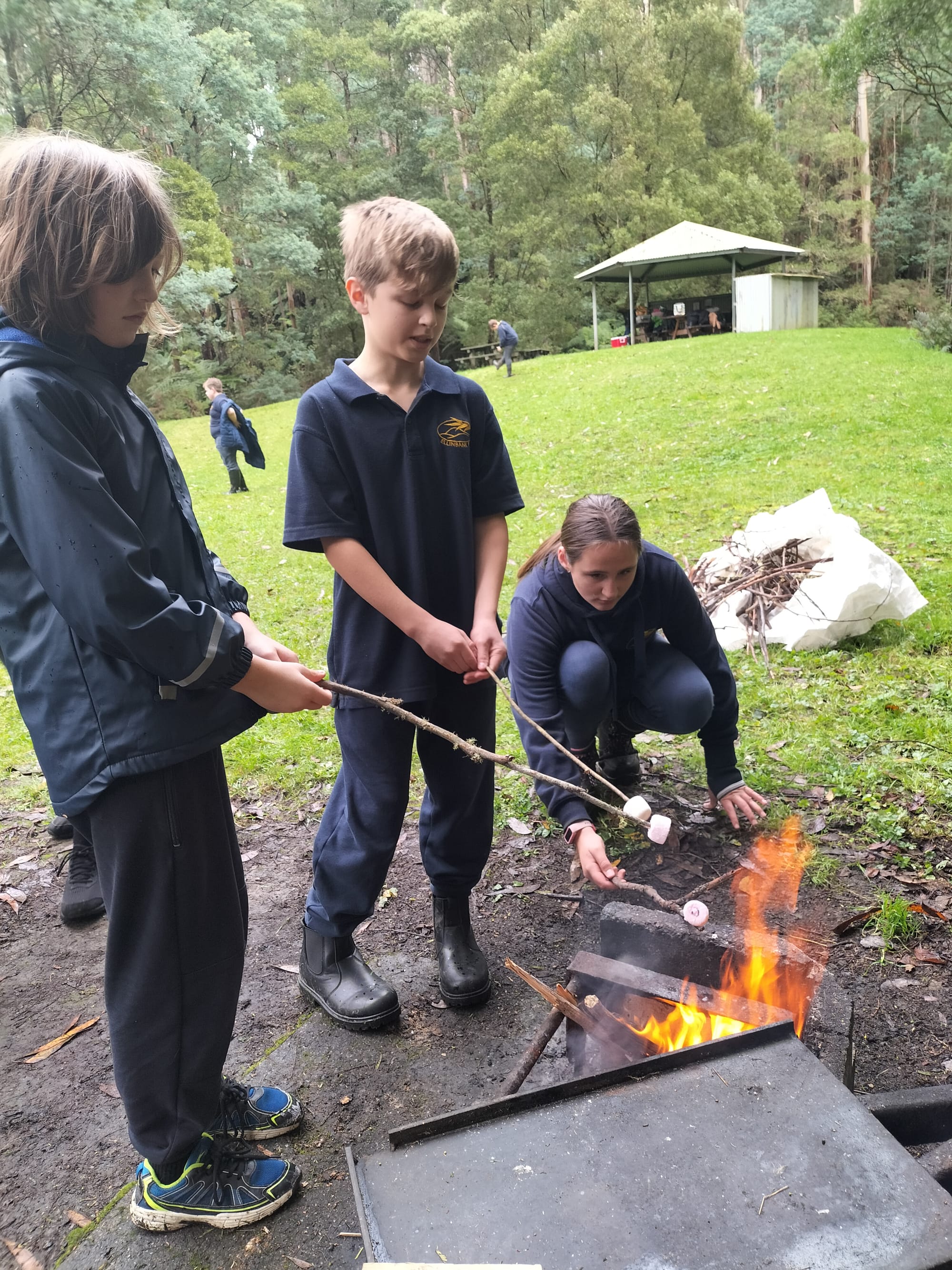 Max Foley, Kelly Rippon-Milner and Jasmine Olsson roast marshmallows by the fire.