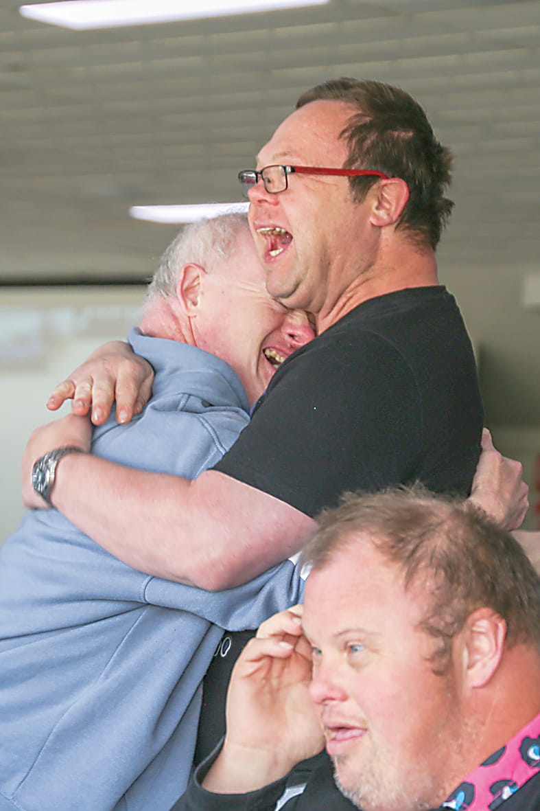 Andrew Prior and Troy Seydak from Lifeskills Victoria embrace, full of joy as they watch their dog win.