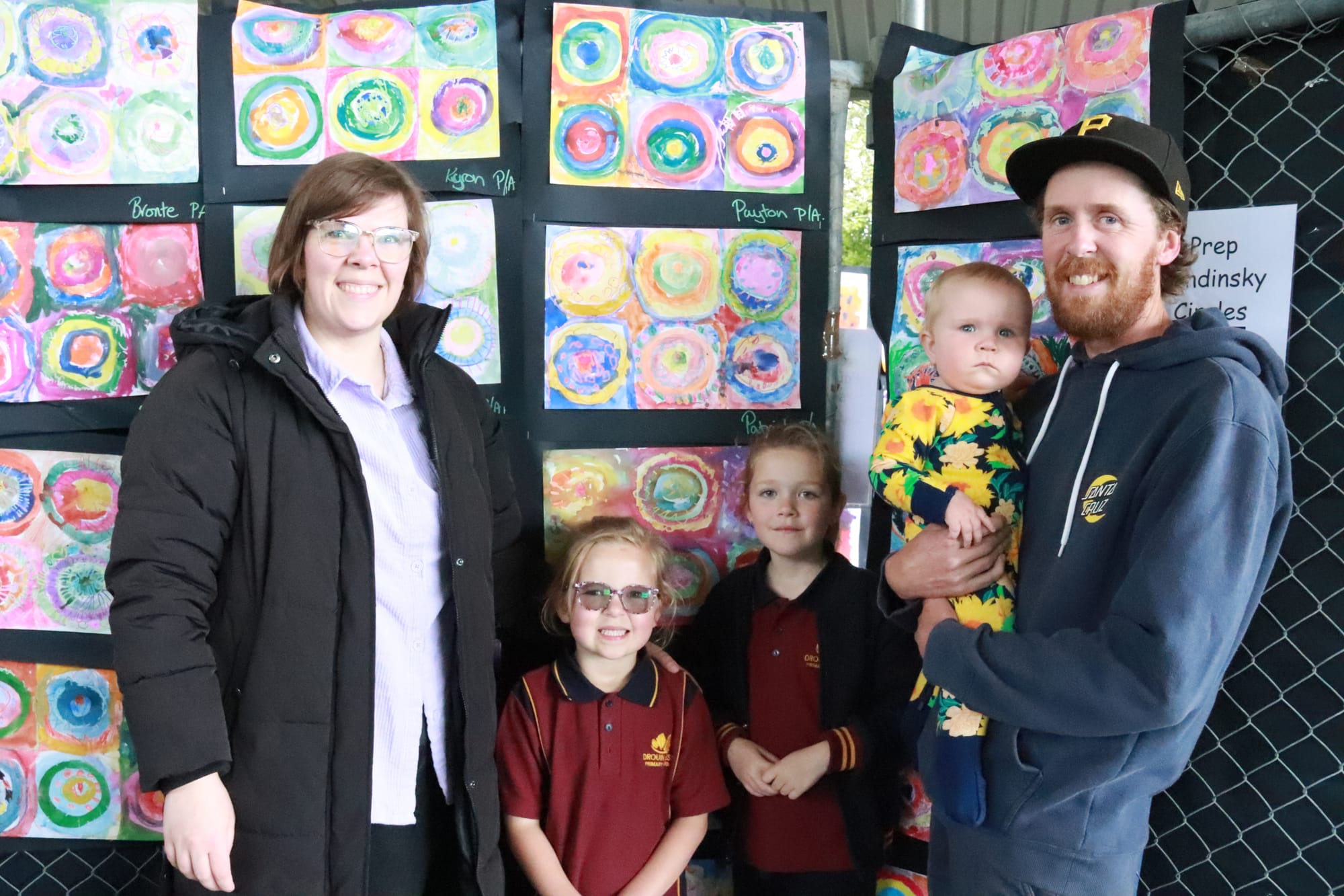 Looking at Kandinsky-inspired circle art at the Drouin West Primary School art show are the Masterson family (from left) Jordan, Peyton, Maxie and Clint holding Tanah.