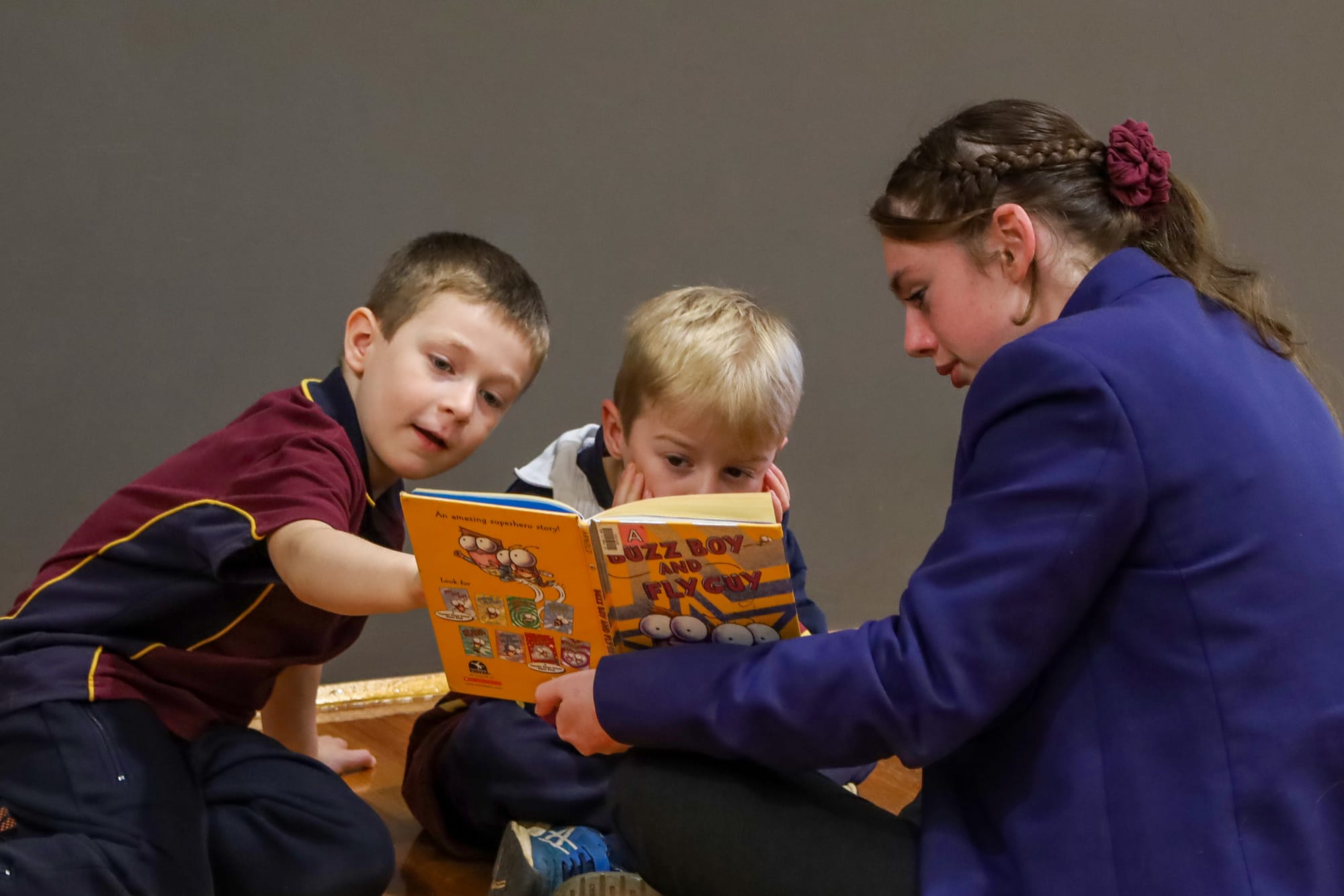 Year 10 student Regan Smith (right) reads to Fletcher Weymouth and Ethan Joyce-Biss.